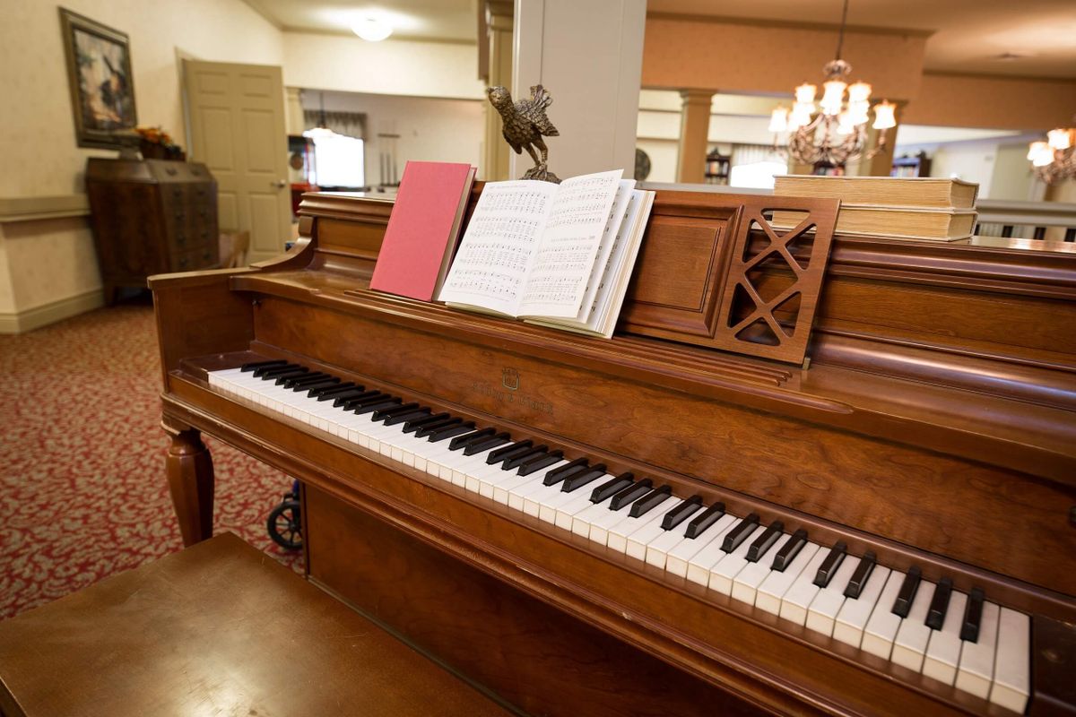 A wooden piano with sheet music set up, ready for playing.