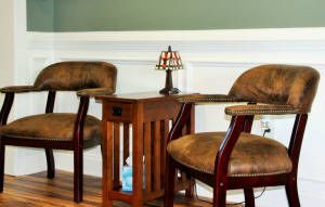 A cozy seating area with two upholstered chairs flanking a wooden side table and a decorative lamp.