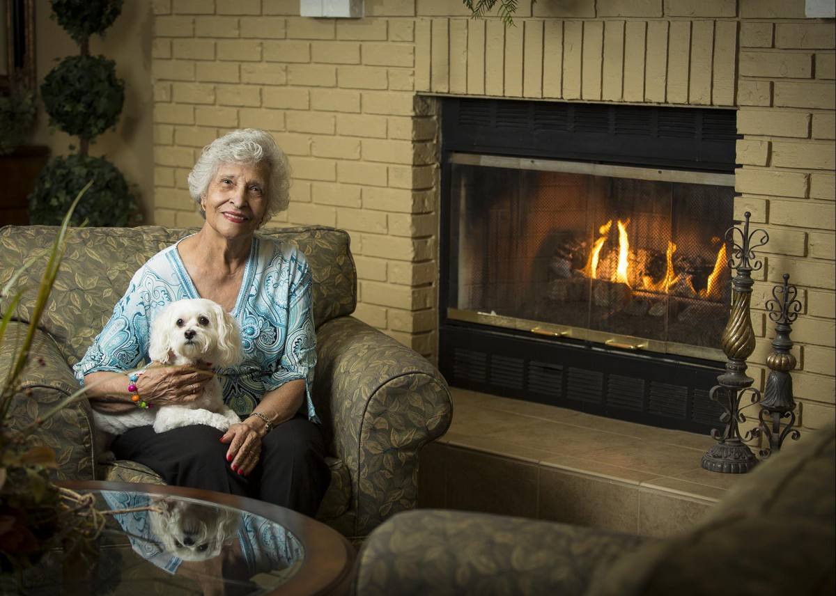 A woman sits by the fireplace with her dog, enjoying a cozy evening.