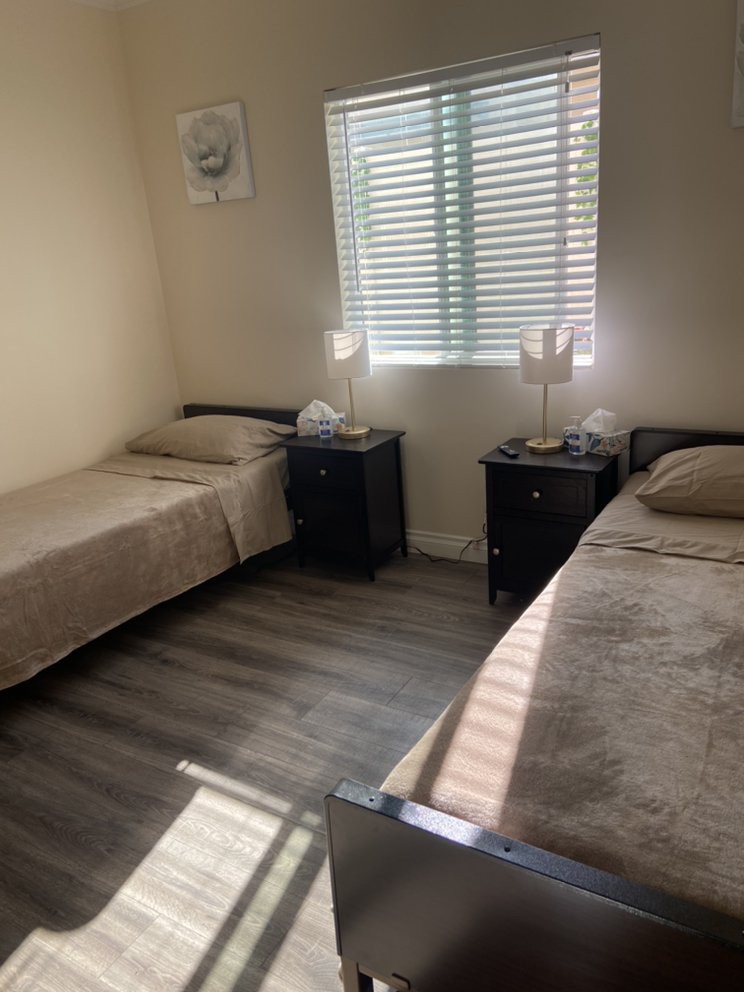 A cozy bedroom featuring two twin beds with matching nightstands and lamps by the window.