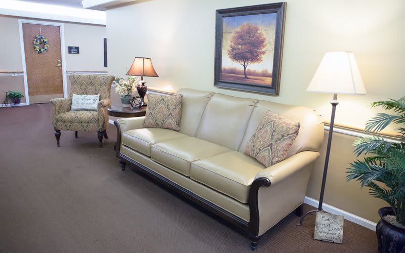A cozy living room featuring a beige sofa with decorative pillows, flanked by table lamps and adorned with wall art.