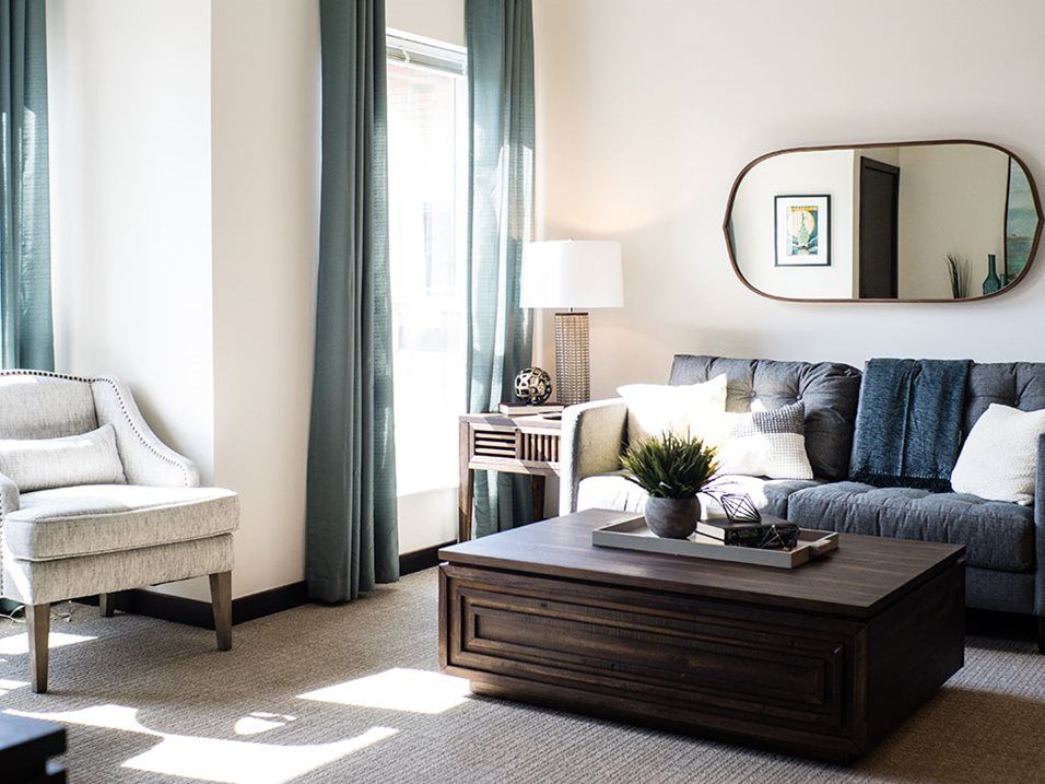 A modern living room featuring a comfortable sofa, large coffee table, and abundant natural light.