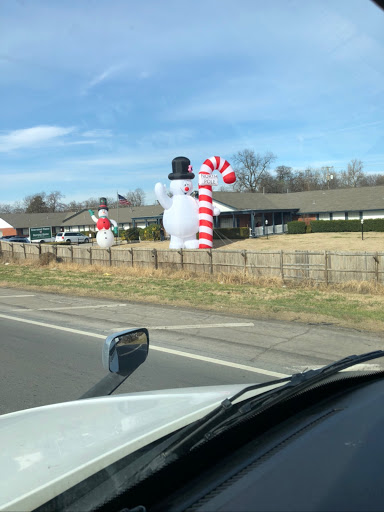 Festive decorations featuring inflatable snowmen and a candy cane along the roadside.