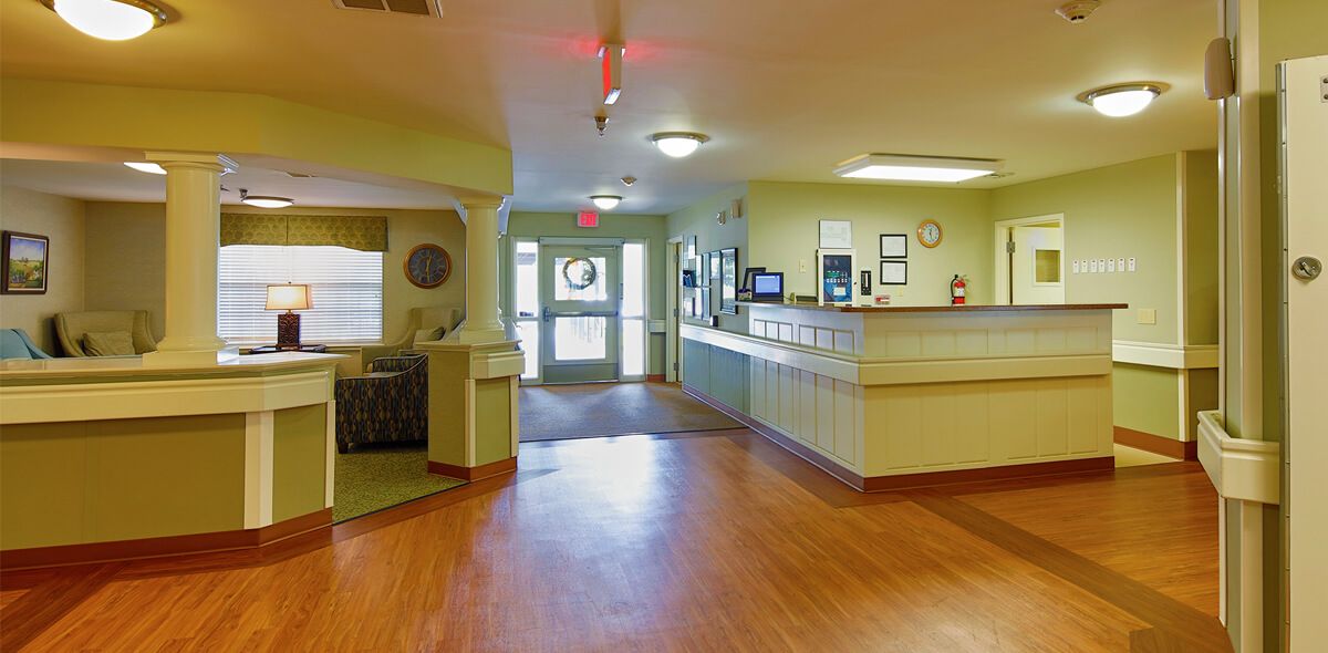A view of a reception area with light green walls and wooden flooring.