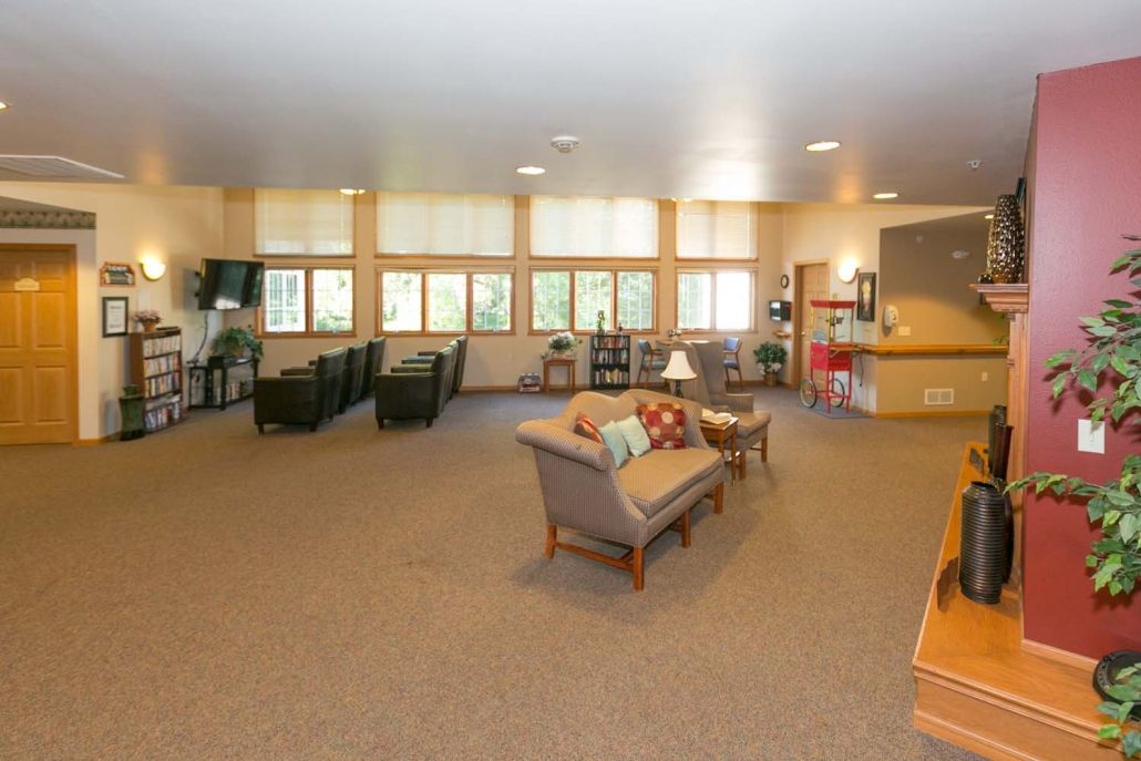A spacious living room with sofas, chairs, and multiple windows providing ample natural light.