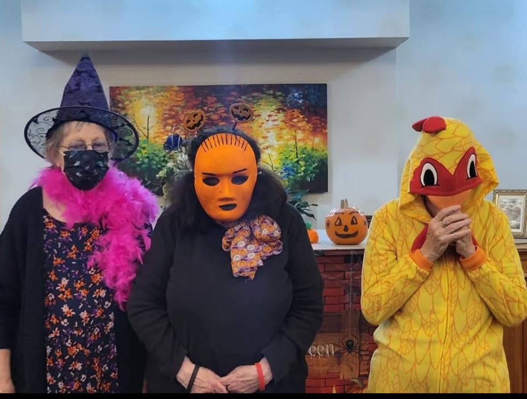 Three people in Halloween costumes: a witch, a pumpkin, and a chicken.
