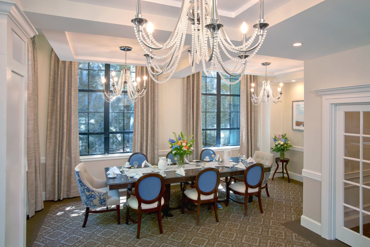 An elegantly decorated dining room with blue chairs and chandeliers.