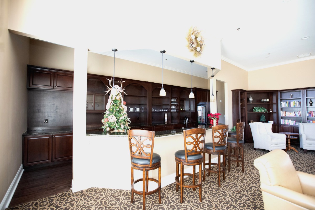 A modern kitchen with a countertop bar and bar stools, decorated for the holidays.