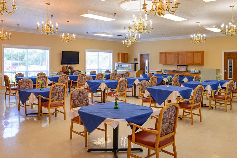 A well-lit dining room with blue tablecloths and elegant chandeliers.