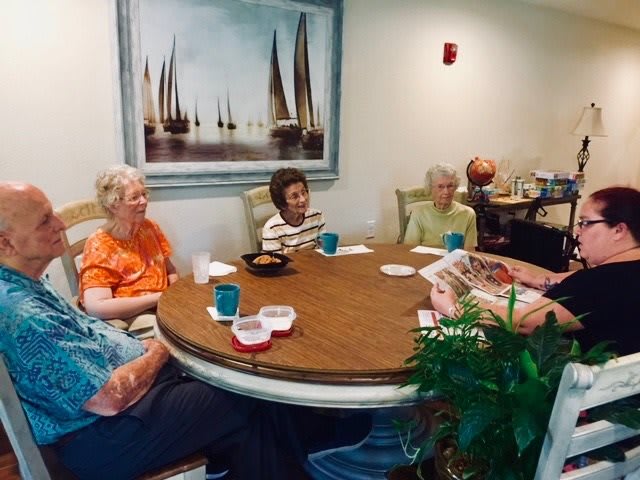 A group of seniors sitting around a table playing a card game indoors.