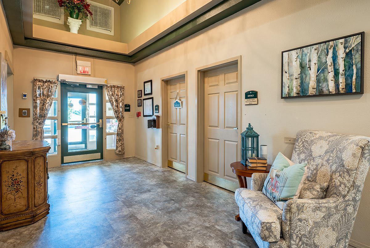 A cozy hallway featuring decorative artwork, seating, and two closed doors.