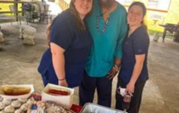 A group of people standing together at an outdoor event with food.