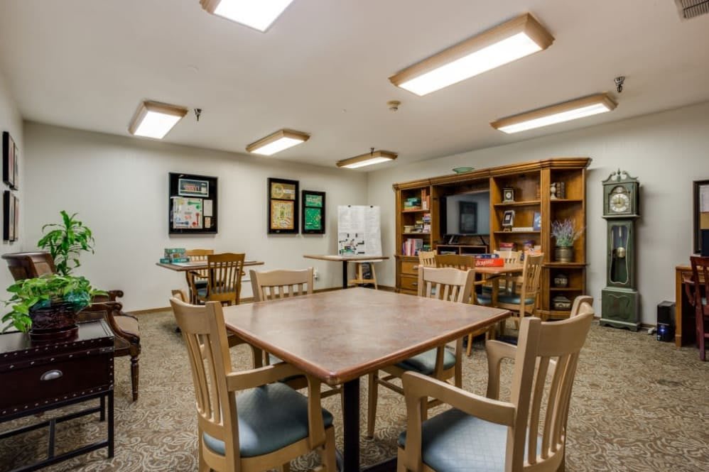 A cozy meeting room featuring bookshelves, tables, and chairs under bright overhead lighting.