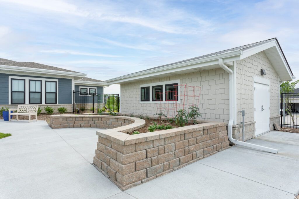 A modern house with a landscaped patio and brick retaining wall.