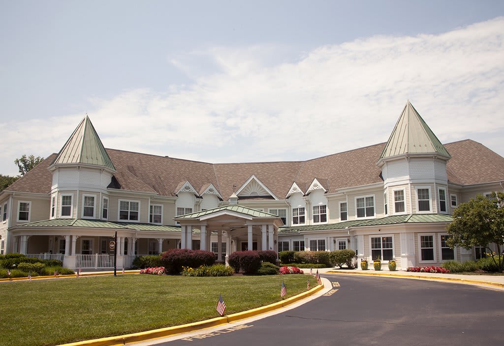 A large residential building with distinctive roofs and a landscaped driveway.