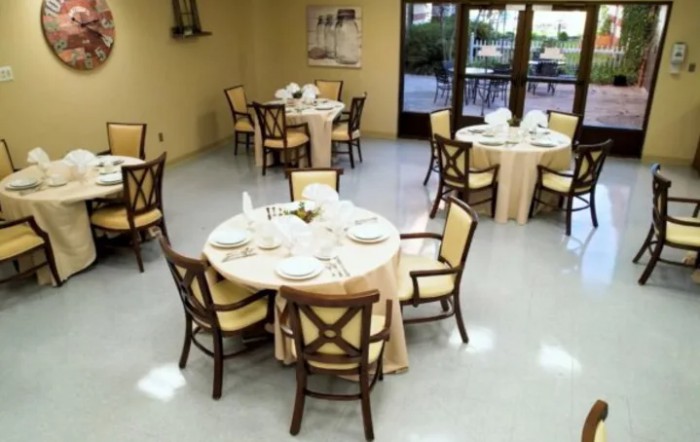 A dining area with round tables and chairs set up for an event or meal.