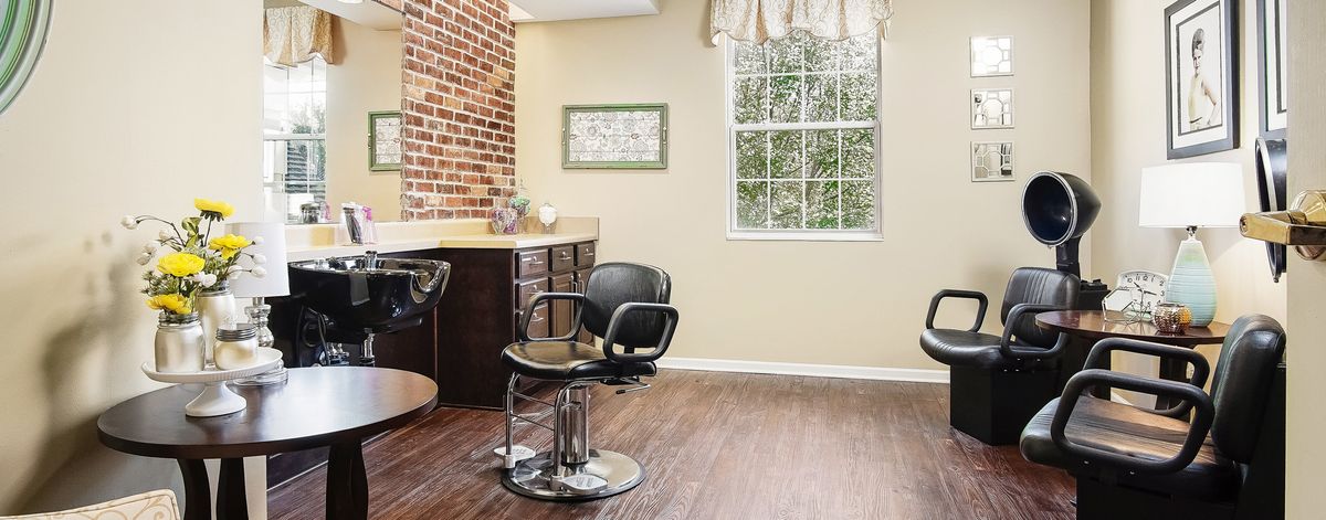 A well-lit hair salon interior with stylish chairs and a brick accent wall.