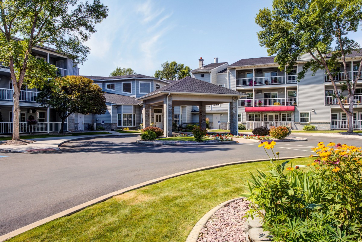 A modern residential building with a landscaped entrance and sunny surroundings.