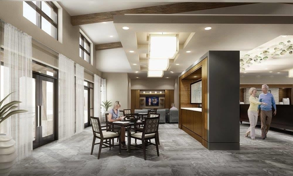 A modern lobby with a seating area featuring tables and chairs, accented by stylish lighting.