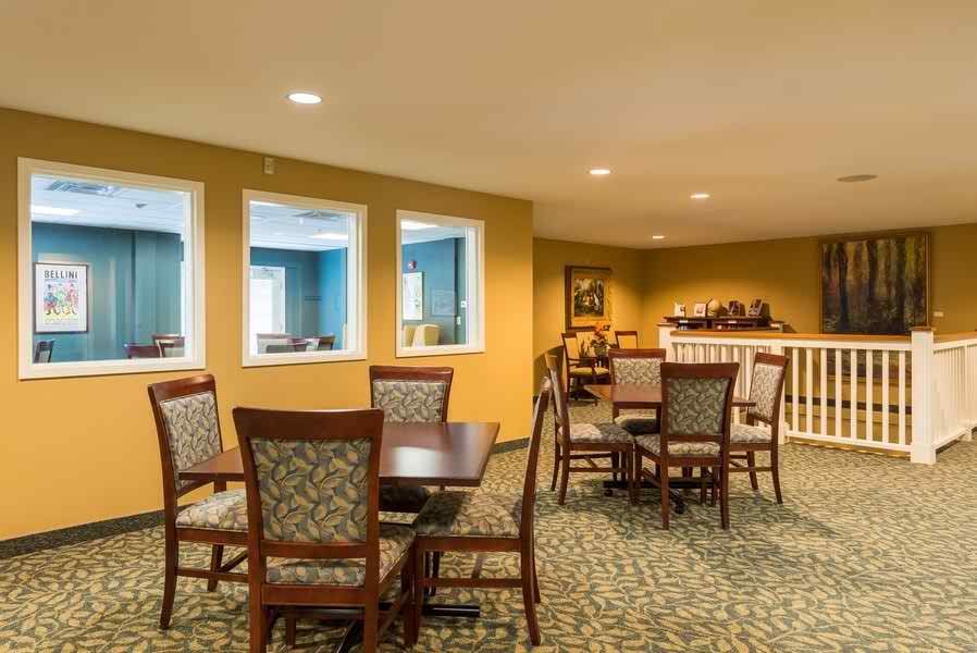 A cozy dining area with tables and chairs arranged on a carpeted floor.