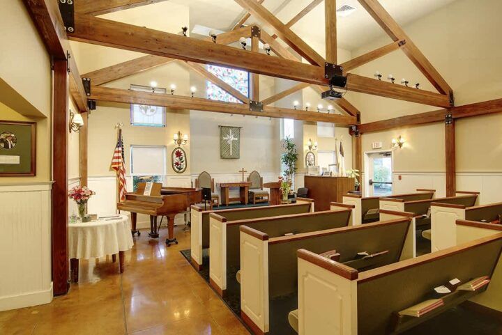 Interior view of a church with wooden pews and visible ceiling beams.