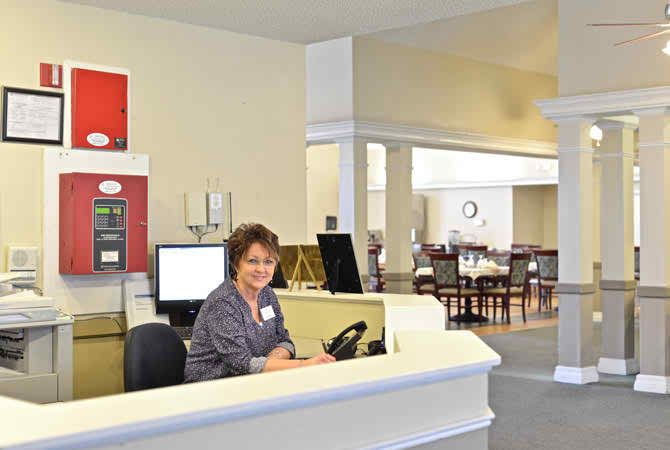 A friendly receptionist at the front desk in an office setting.