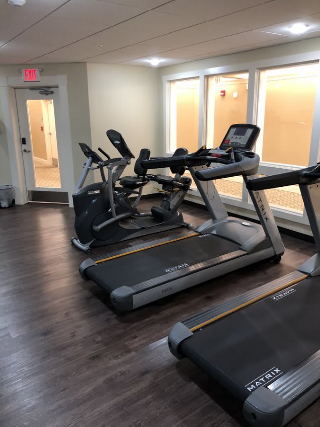 A gym room with treadmills and stationary bikes ready for use.