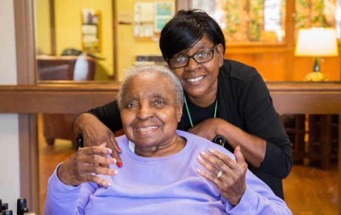 An elderly person and their caregiver smiling together, showcasing companionship and support.
