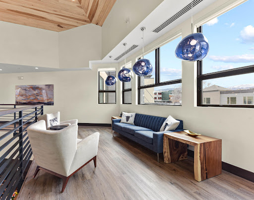 A modern living room featuring stylish blue pendant lights, a comfortable sofa, and large windows allowing ample natural light.