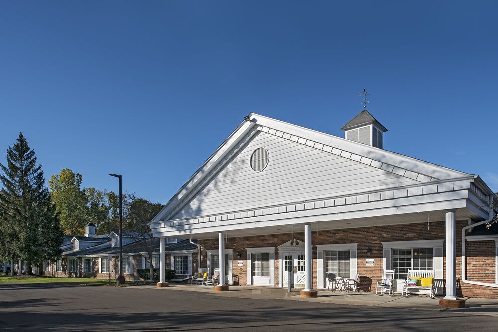 A large white building with a porch and columns, set against a clear blue sky.