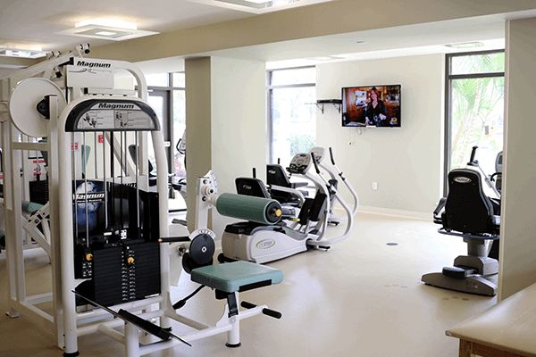 A well-equipped gym featuring various exercise machines including treadmills, stationary bikes, and weight equipment.