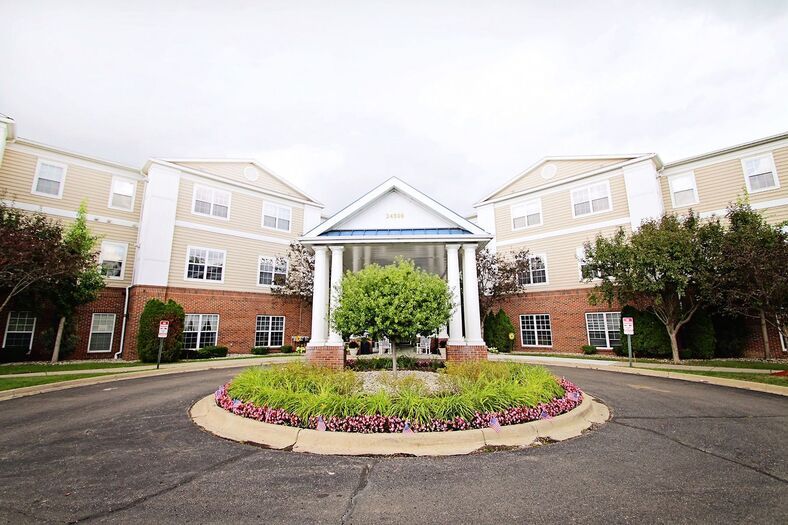 Front view of a residential building with a landscaped entrance and circular driveway.