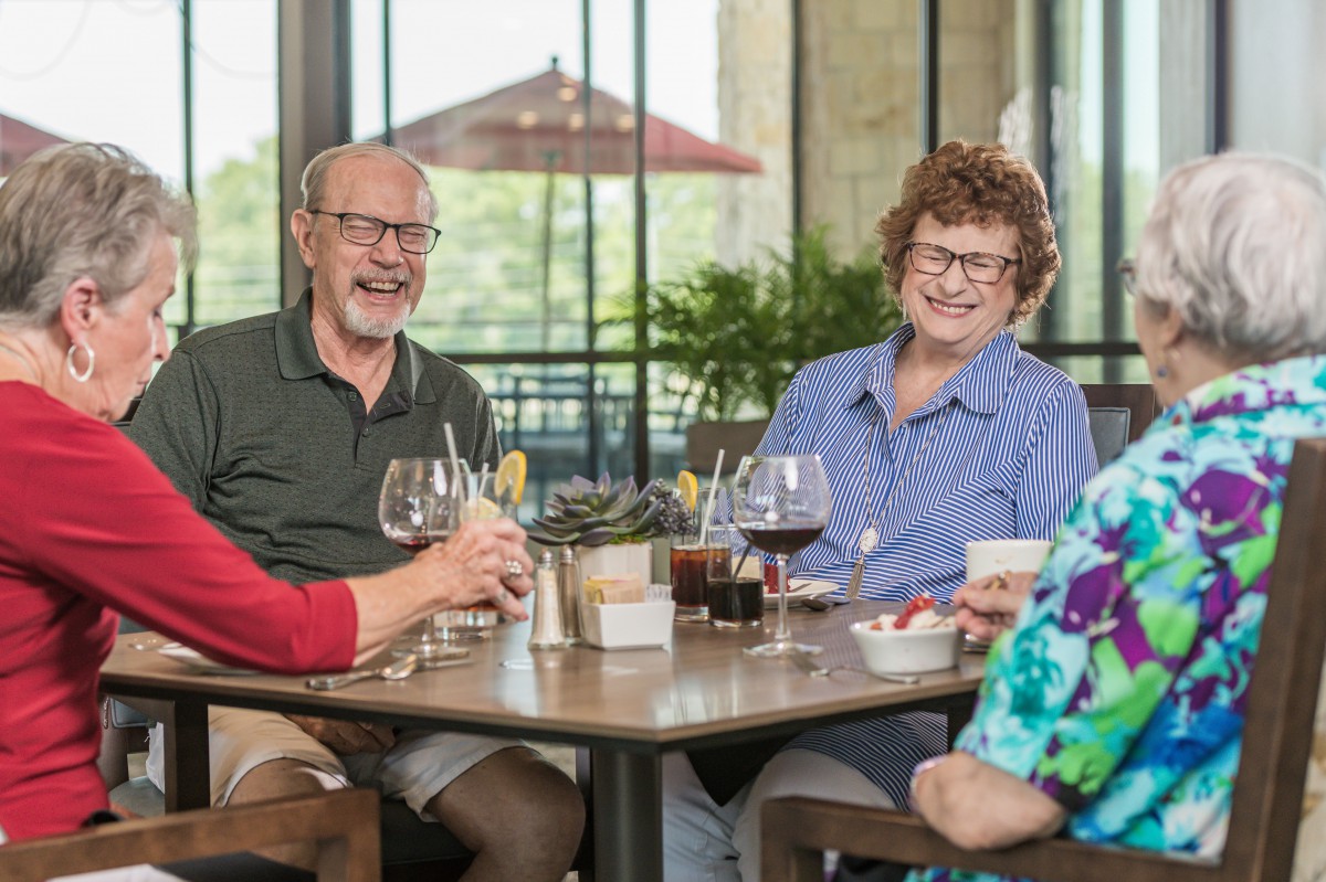 A group of seniors enjoying a social gathering at a restaurant, sharing laughter and drinks.