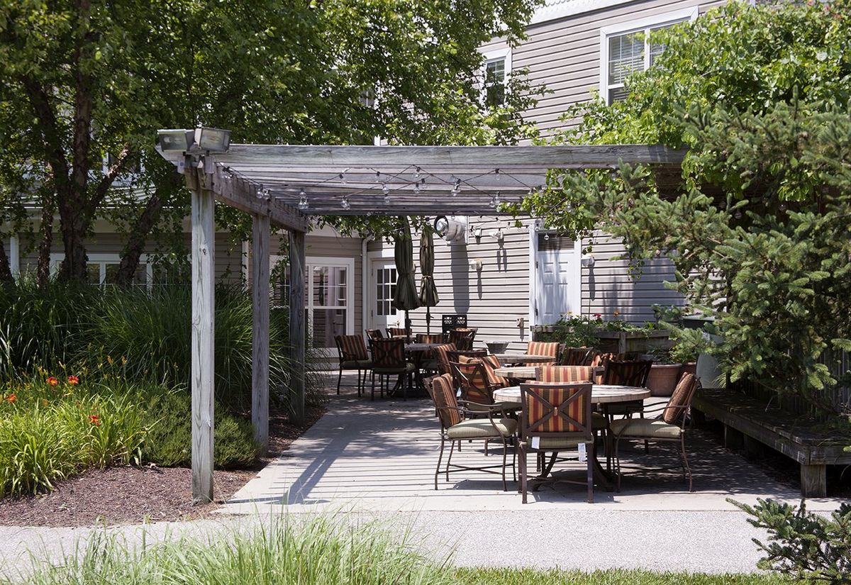 Outdoor patio area with chairs and tables under a pergola.