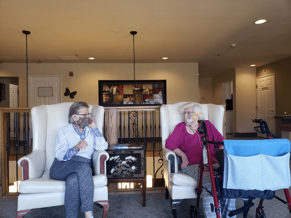 Two elderly individuals sitting in a living room having a conversation.