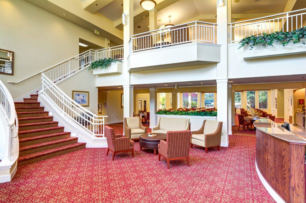 A spacious hotel lobby featuring comfortable seating and a grand staircase.