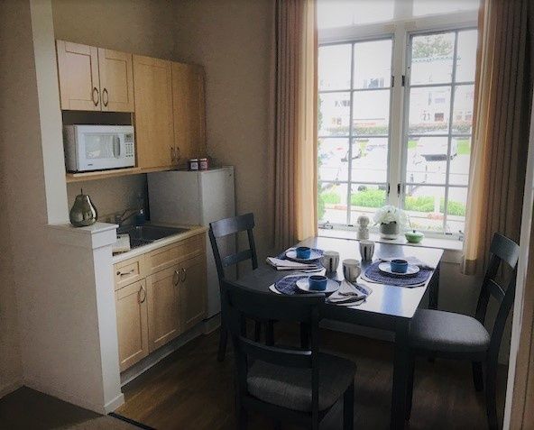 A cozy kitchen and dining area with a table set for two, featuring a large window that lets in natural light.