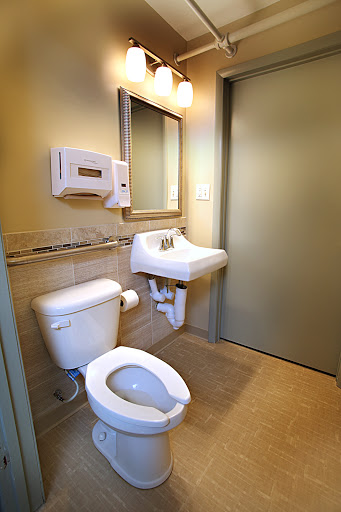 A clean and modern bathroom featuring a toilet, sink, mirror, and hand dryer.