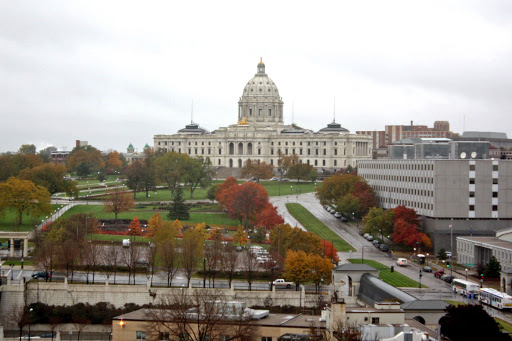 The Capitol building surrounded by autumn foliage on a cloudy day.