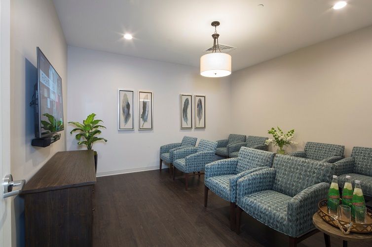 A cozy waiting room with blue patterned chairs and wall art.