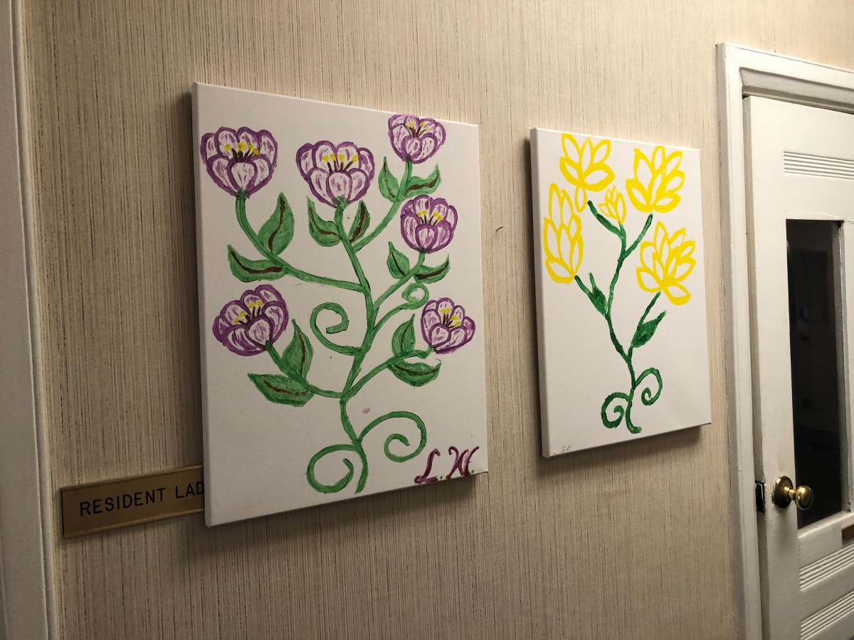 Colorful floral paintings displayed on a wall.