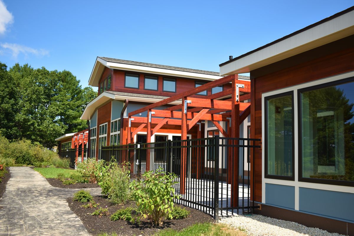 A modern building with redwood design elements and large windows surrounded by neatly maintained landscaping.