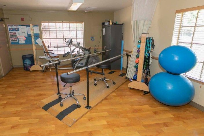 A physical therapy room equipped with parallel bars and stability balls for rehabilitation exercises.