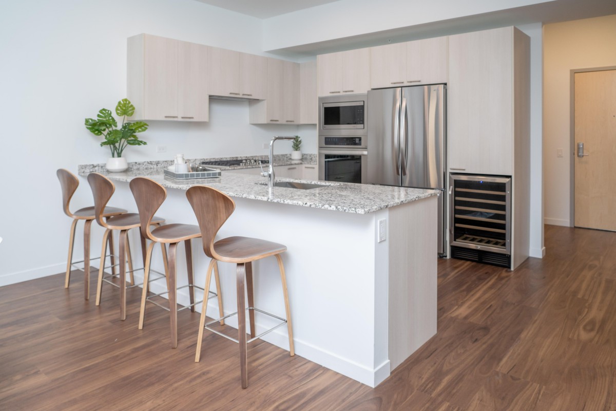 A modern kitchen with a large island, bar stools, and stainless steel appliances.