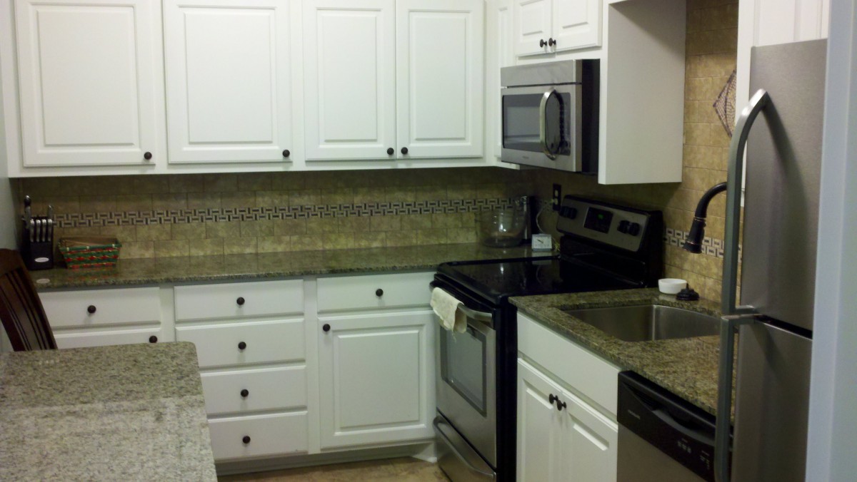 A modern kitchen with white cabinets and stainless steel appliances.