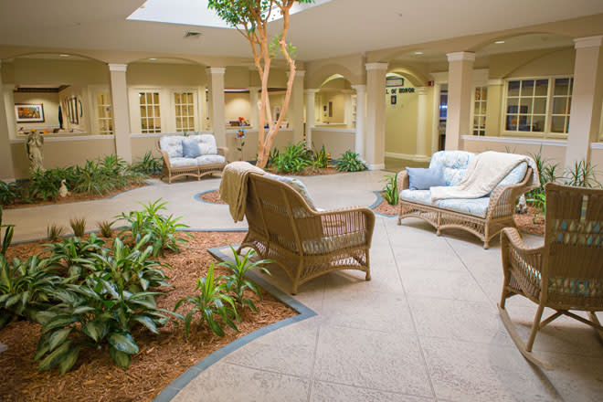 A cozy indoor courtyard featuring wicker furniture and lush plants.