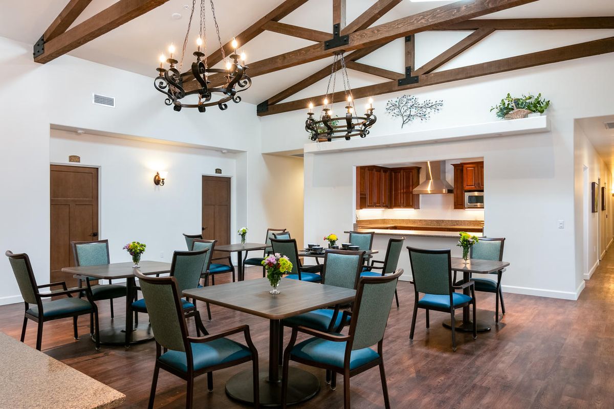 A well-lit dining area with wooden beams and elegant chandeliers.