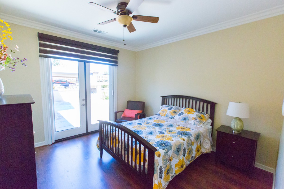 A cozy bedroom with a wooden bed, colorful bedding, and a ceiling fan.