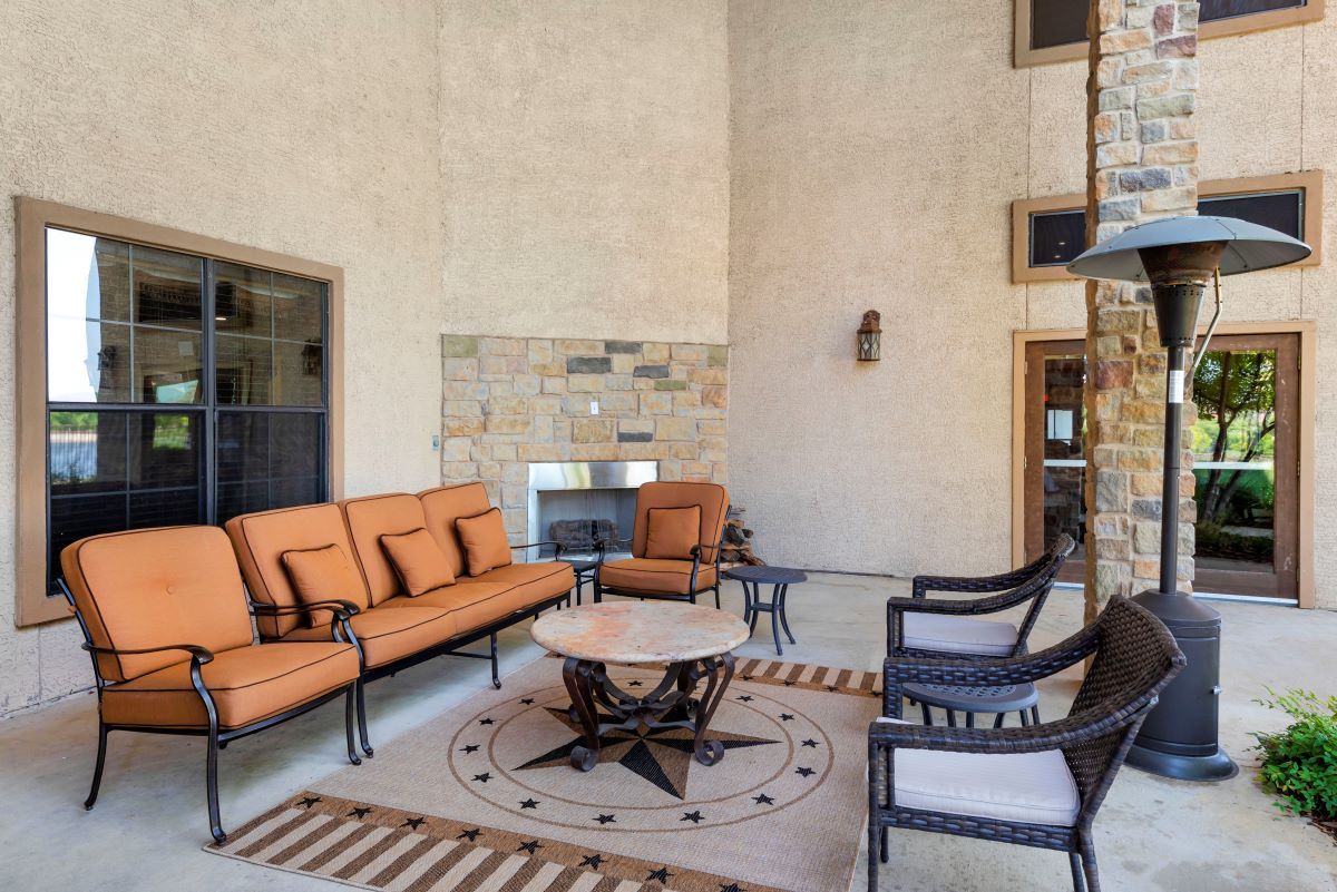 A modern outdoor patio with comfortable seating and a fireplace.