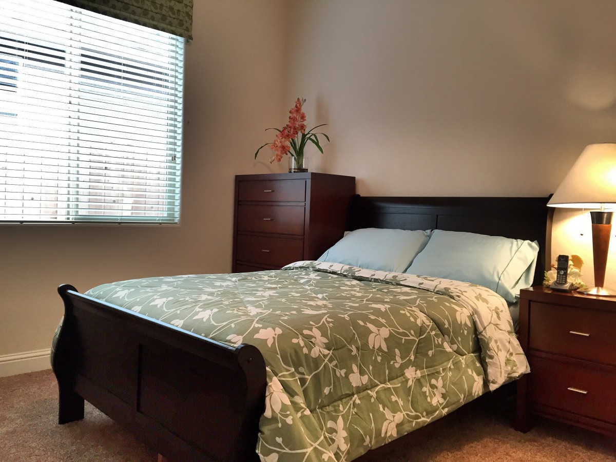A cozy bedroom with a bed, dresser, and window.